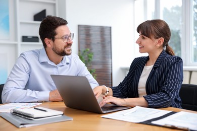 Photo of Consultant working with client at table in office. Business meeting