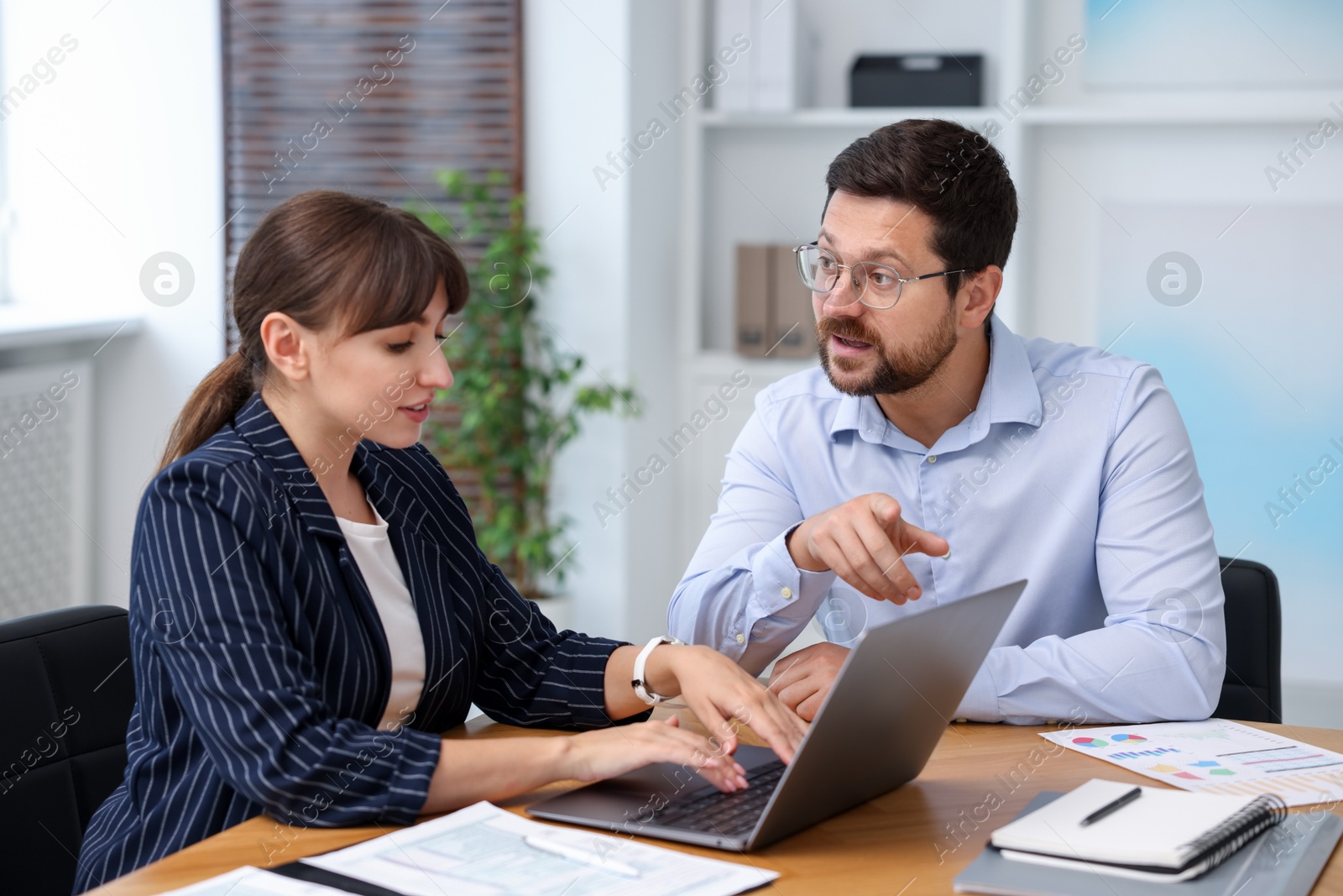 Photo of Consultant working with client at table in office. Business meeting
