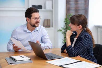 Photo of Consultant working with client at table in office. Business meeting