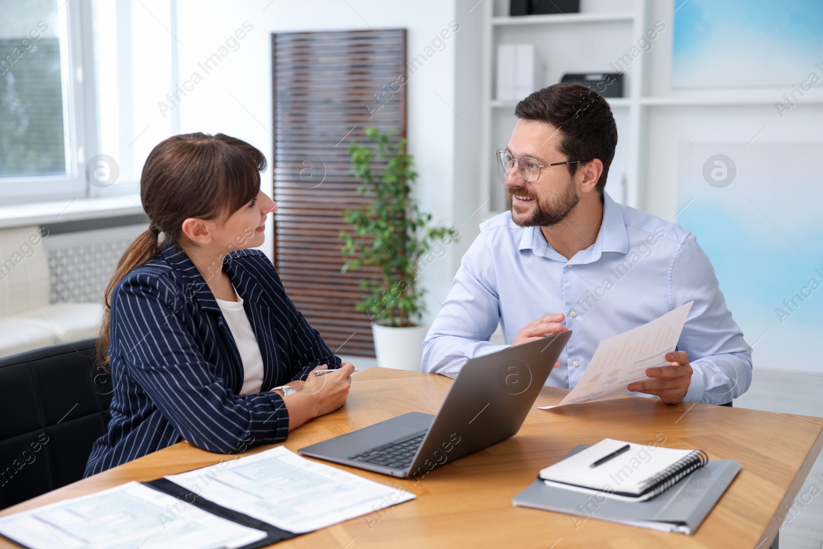 Photo of Consultant working with client at table in office. Business meeting