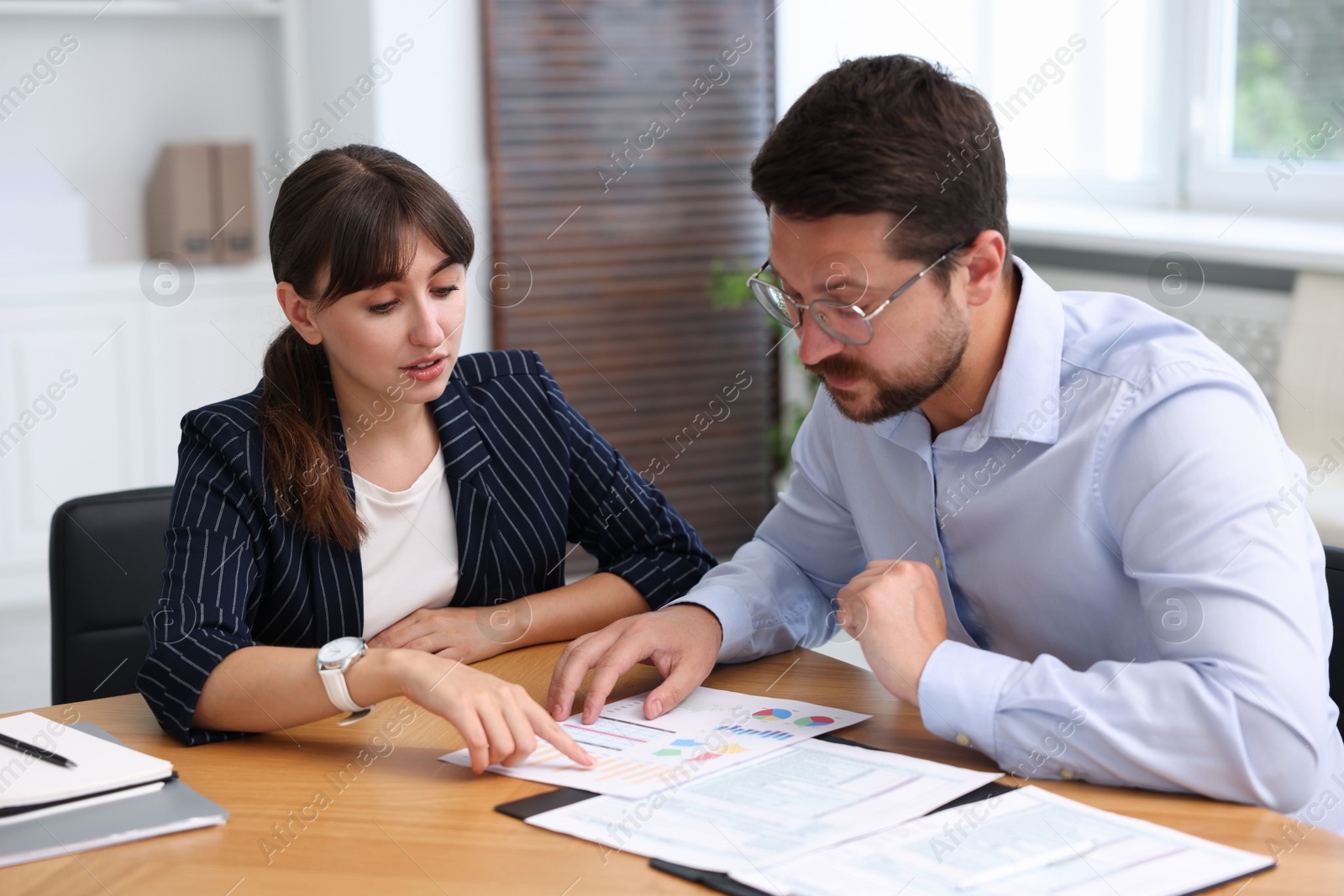 Photo of Consultant working with client at table in office. Business meeting
