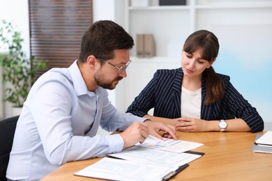 Photo of Consultant working with client at table in office. Business meeting