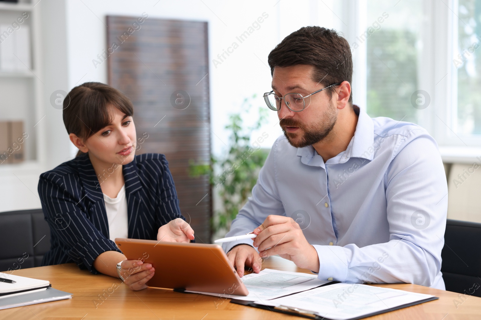 Photo of Consultant working with client at table in office. Business meeting
