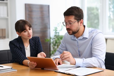 Photo of Consultant working with client at table in office. Business meeting