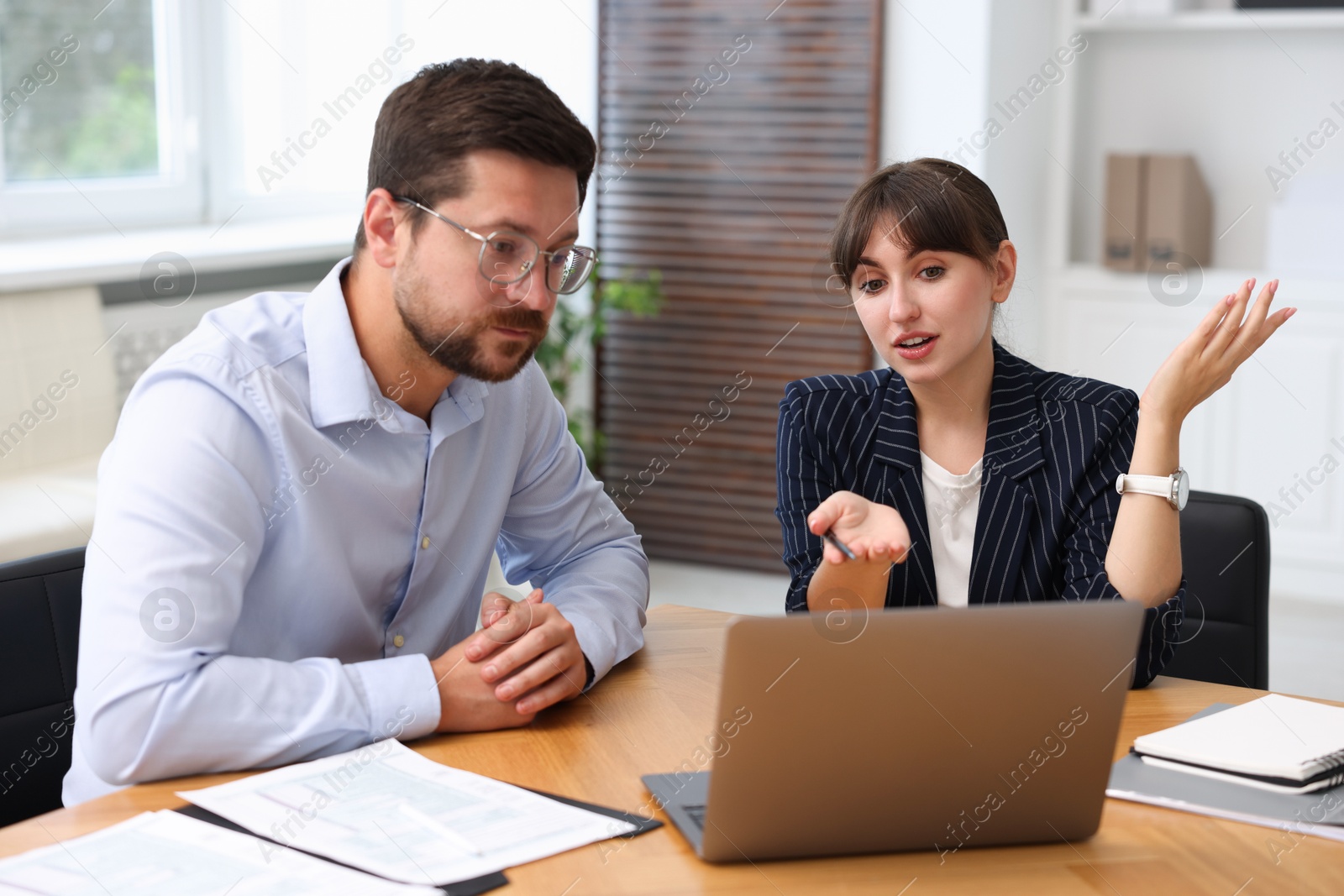 Photo of Consultant working with client at table in office. Business meeting
