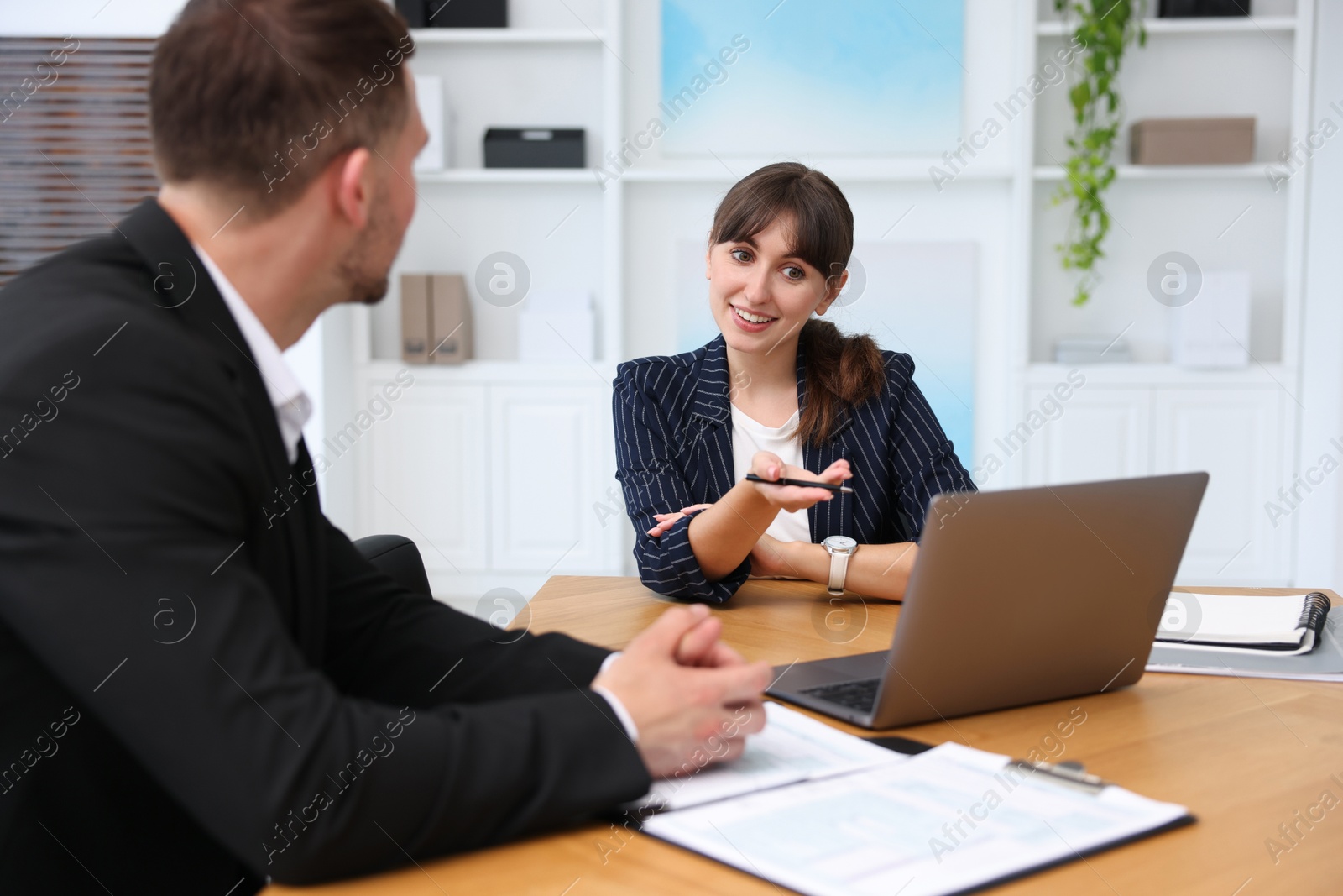 Photo of Consultant working with client at table in office. Business meeting