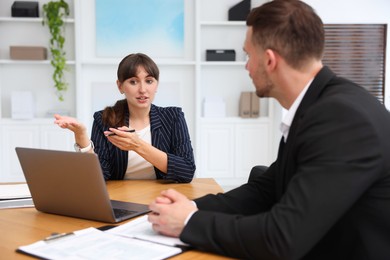 Photo of Consultant working with client at table in office. Business meeting