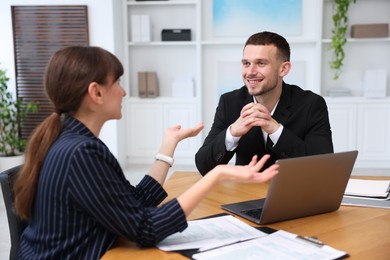 Photo of Consultant working with client at table in office. Business meeting