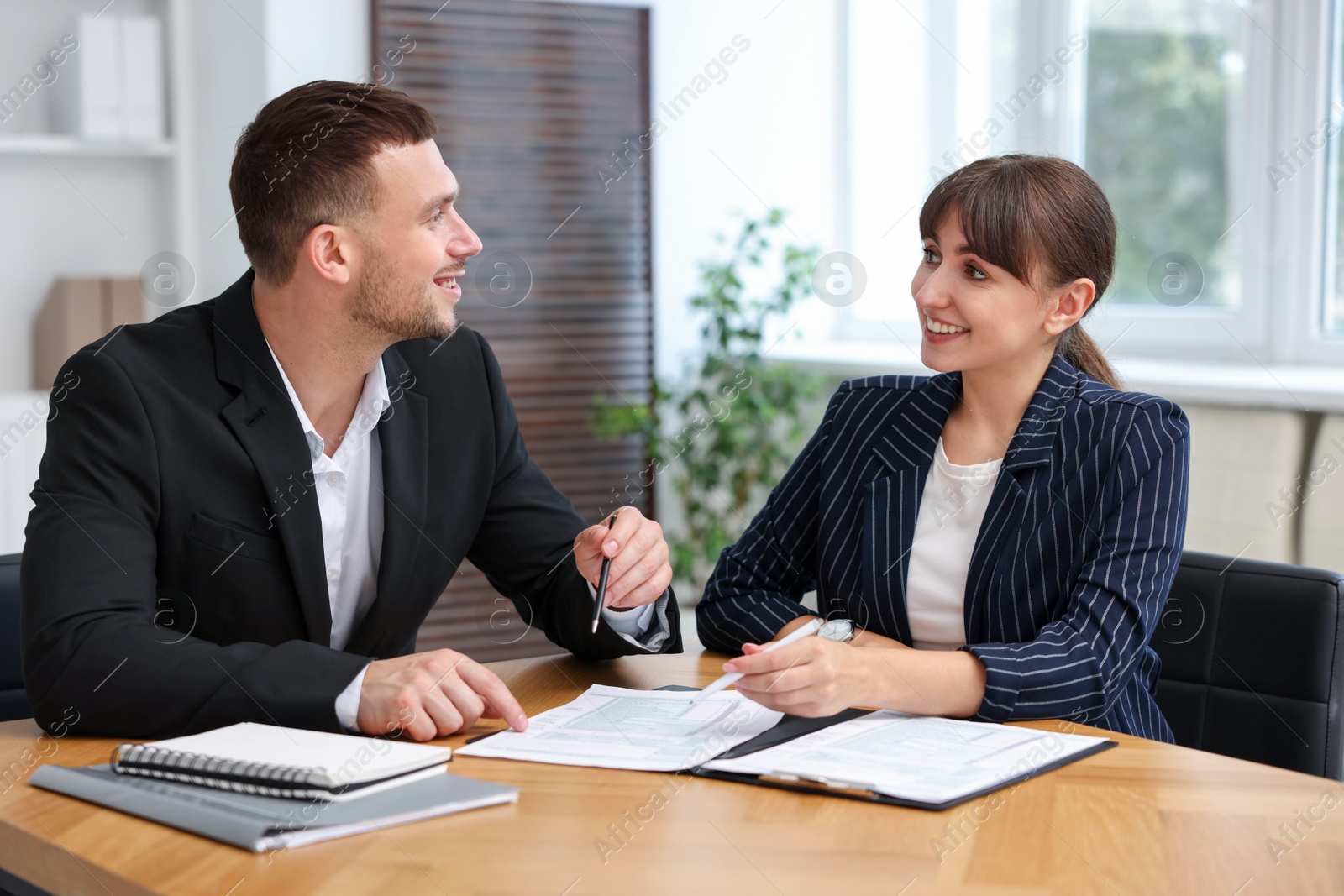 Photo of Consultant working with client at table in office. Business meeting