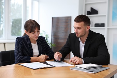 Photo of Consultant working with client at table in office. Business meeting