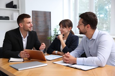 Photo of Couple having meeting with business consultant at table in office