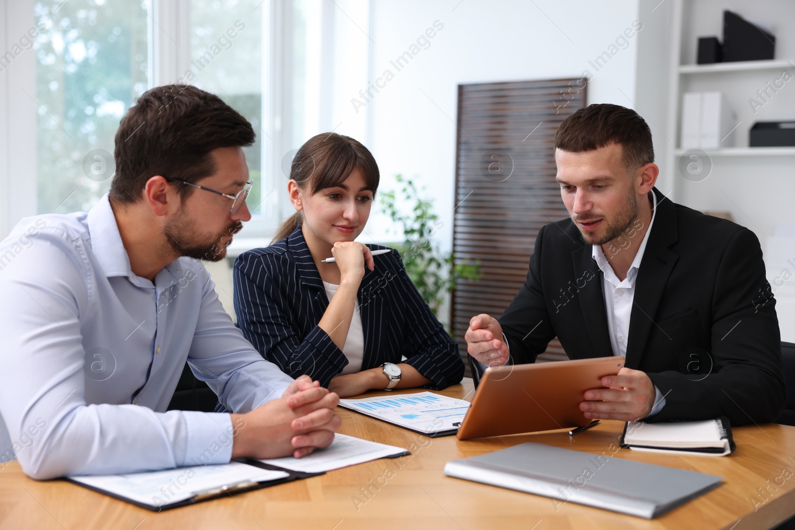 Photo of Couple having meeting with business consultant at table in office