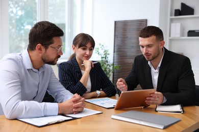 Photo of Couple having meeting with business consultant at table in office