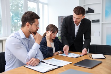 Photo of Couple having meeting with business consultant at table in office