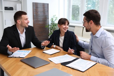 Photo of Couple having meeting with business consultant at table in office