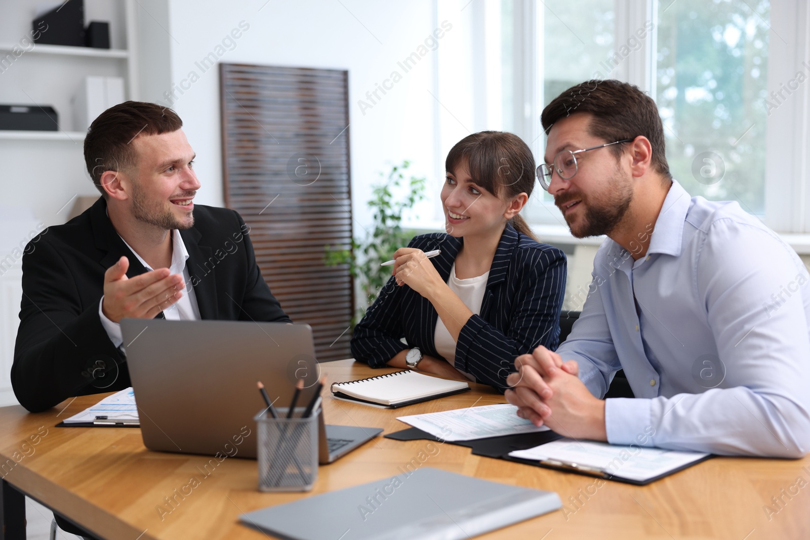 Photo of Couple having meeting with business consultant at table in office