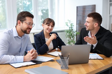 Photo of Couple having meeting with business consultant at table in office