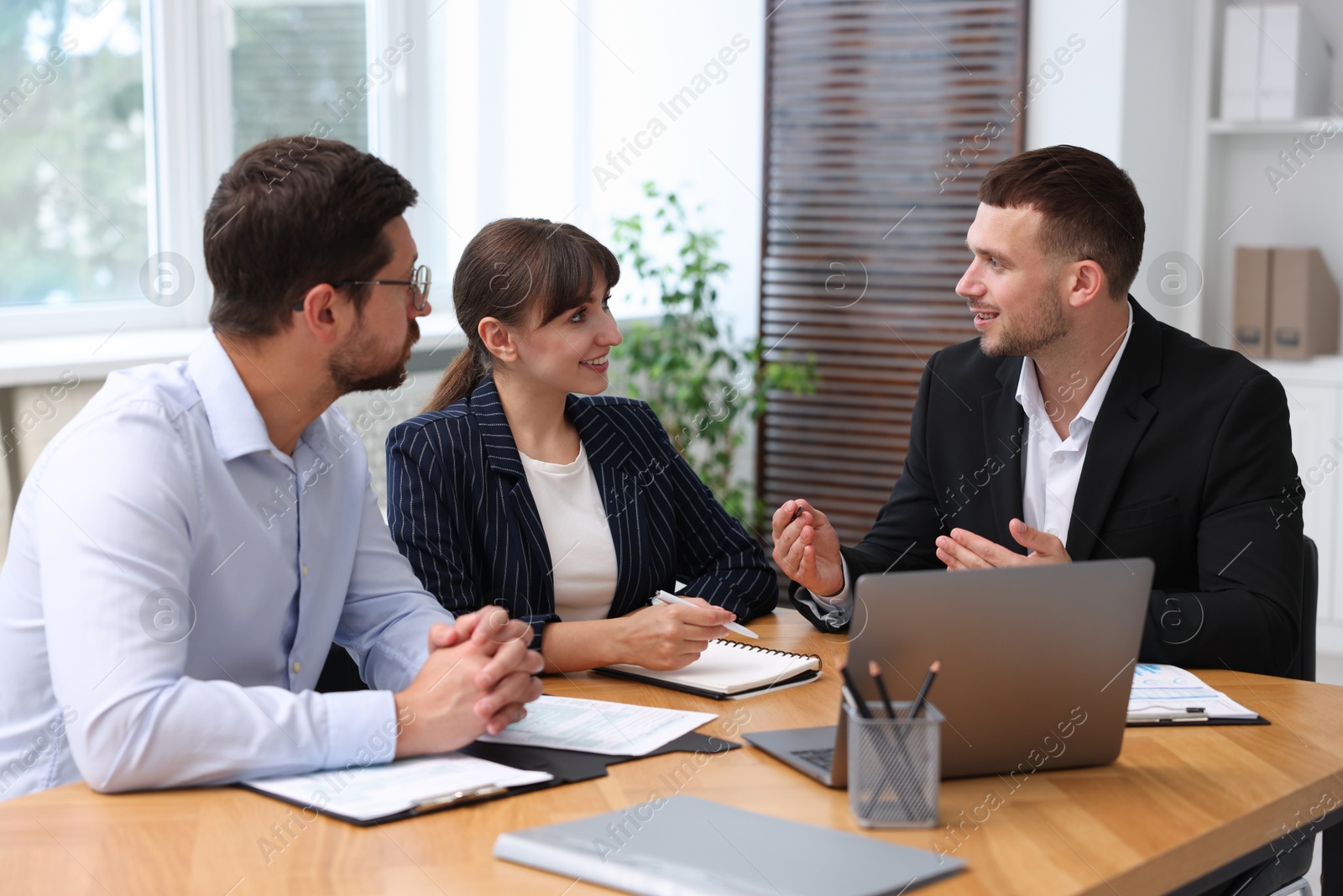 Photo of Couple having meeting with business consultant at table in office