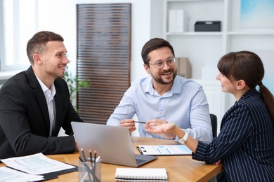 Photo of Couple having meeting with business consultant at table in office