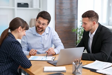 Photo of Couple having meeting with business consultant at table in office