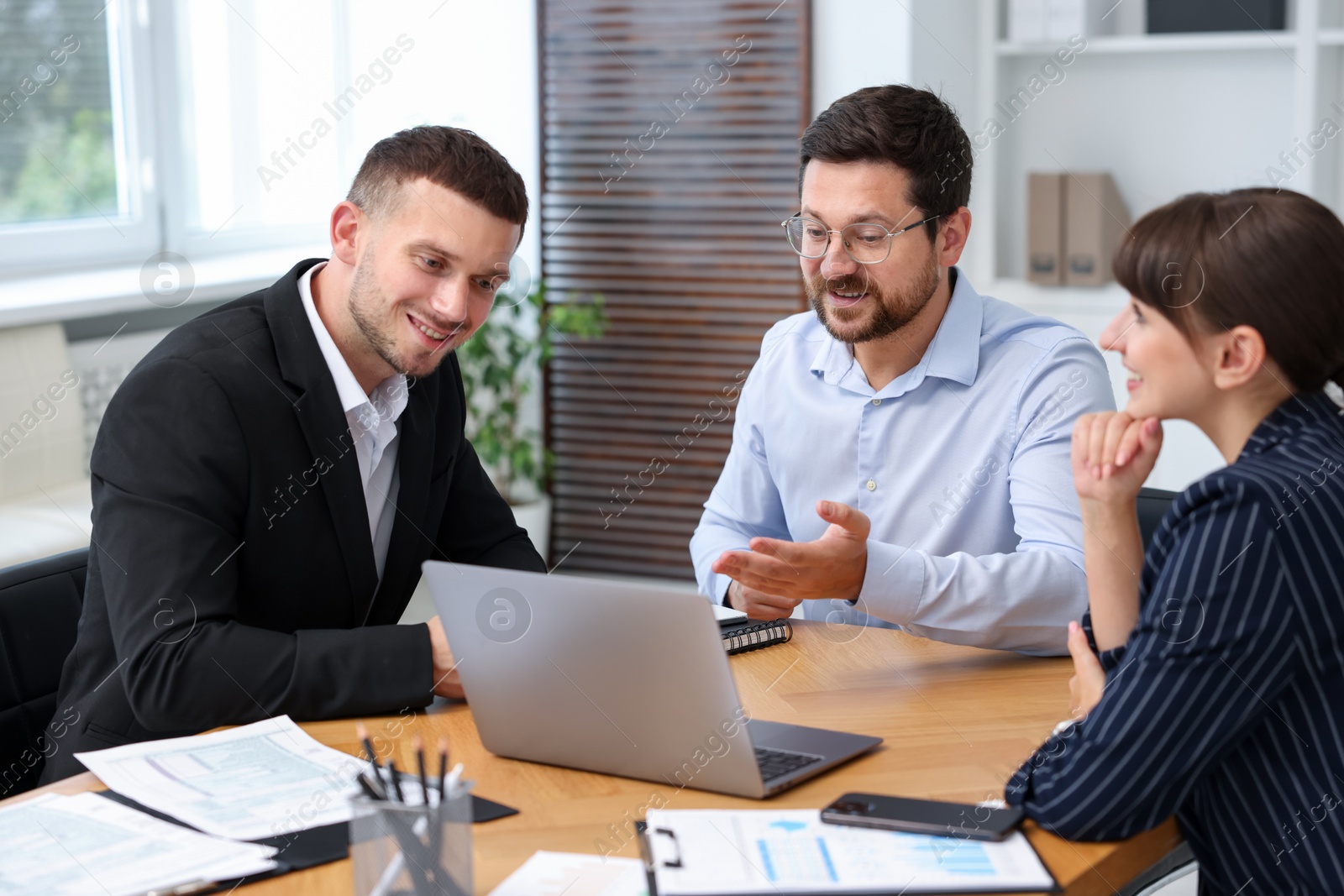 Photo of Couple having meeting with business consultant at table in office