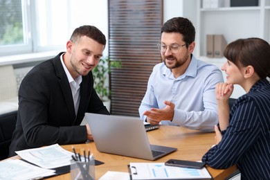 Photo of Couple having meeting with business consultant at table in office