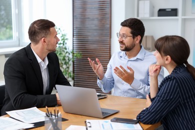 Photo of Couple having meeting with business consultant at table in office