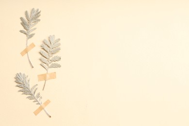 Photo of Beautiful dry leaves with adhesive tape on beige background, flat lay. Space for text