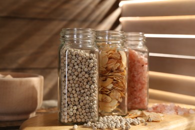 Photo of Different aromatic spices in glass jars on wooden table, closeup