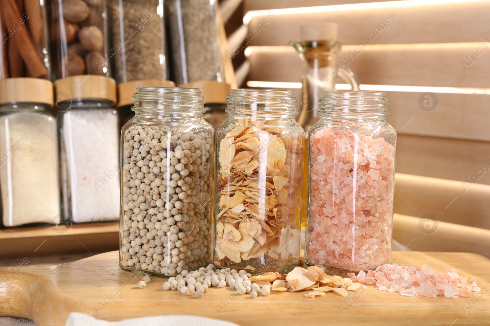 Photo of Different aromatic spices in glass jars on table, closeup