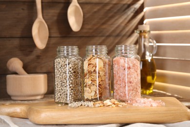 Photo of Different aromatic spices in glass jars on table, closeup