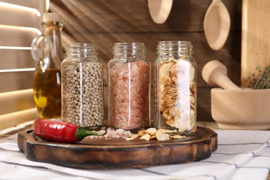 Photo of Different aromatic spices in glass jars on table, closeup