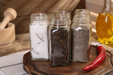 Photo of Different aromatic spices in glass jars on table, closeup