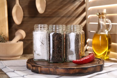 Photo of Different aromatic spices in glass jars on wooden table, closeup