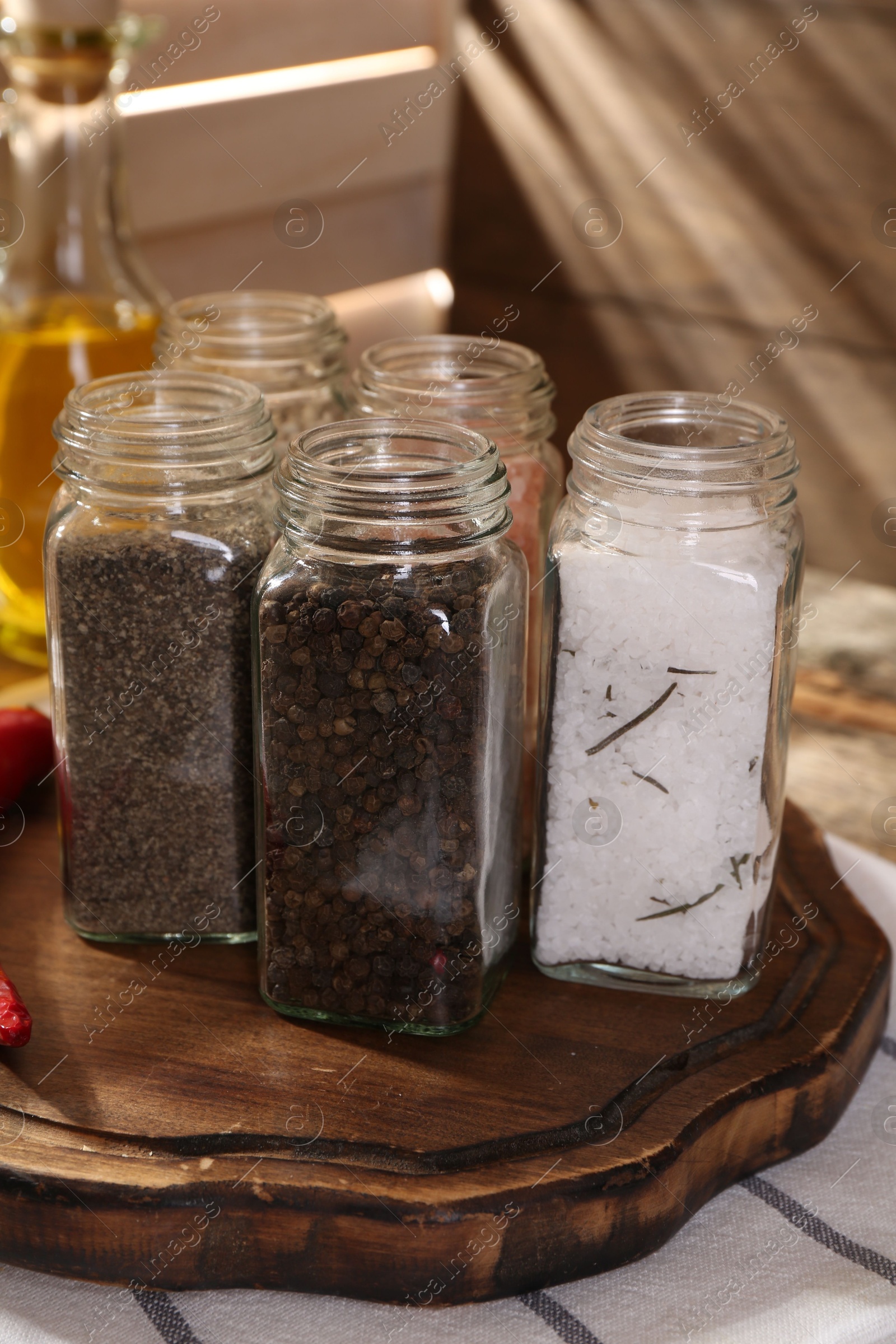 Photo of Different aromatic spices in glass jars on table, closeup