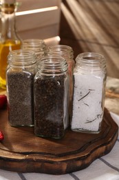 Photo of Different aromatic spices in glass jars on table, closeup