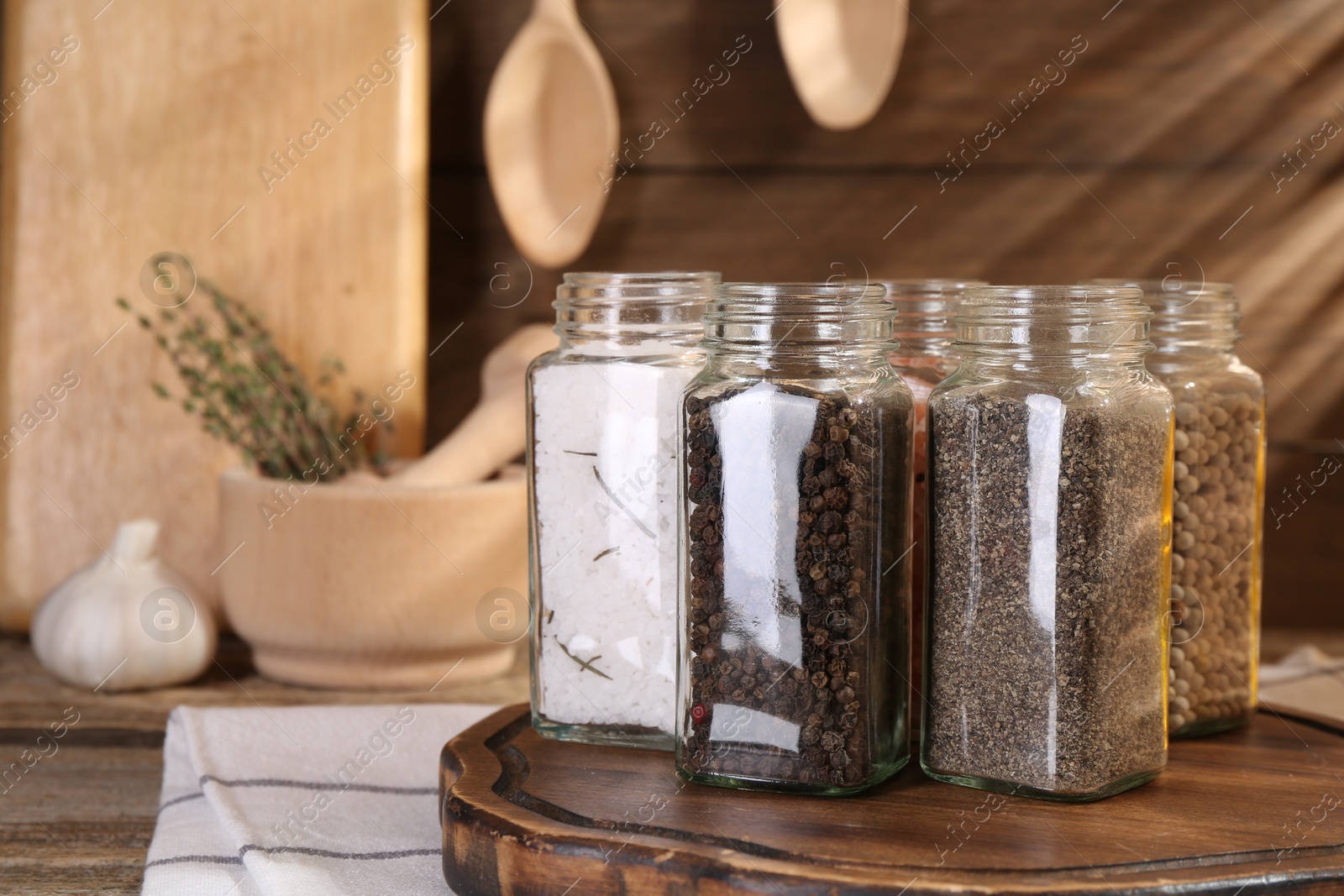 Photo of Different aromatic spices in glass jars on wooden table, closeup
