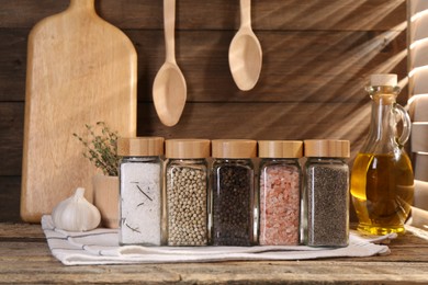 Photo of Different aromatic spices in glass jars on wooden table