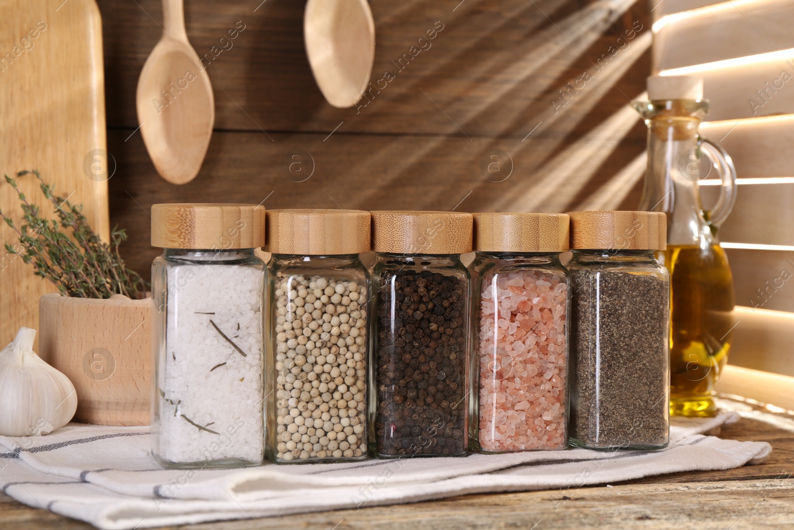 Photo of Different aromatic spices in glass jars on wooden table
