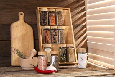 Photo of Different spices in glass jars and on wooden table