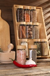 Photo of Different spices in glass jars and on wooden table