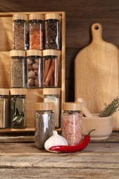 Photo of Different spices in glass jars and on wooden table