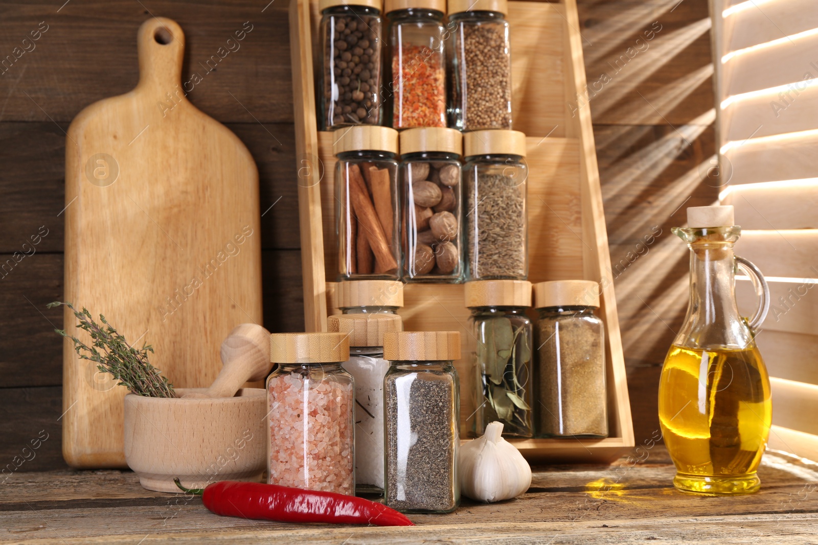 Photo of Different spices in glass jars and on wooden table