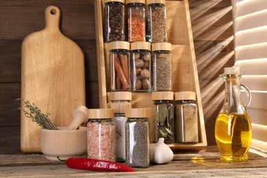 Photo of Different spices in glass jars and on wooden table