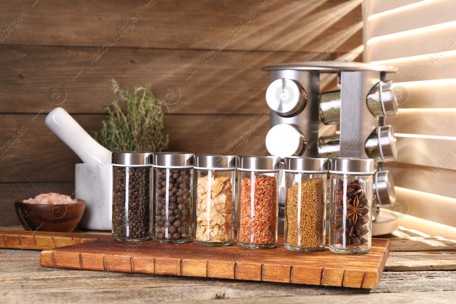 Photo of Different spices in glass jars and on wooden table