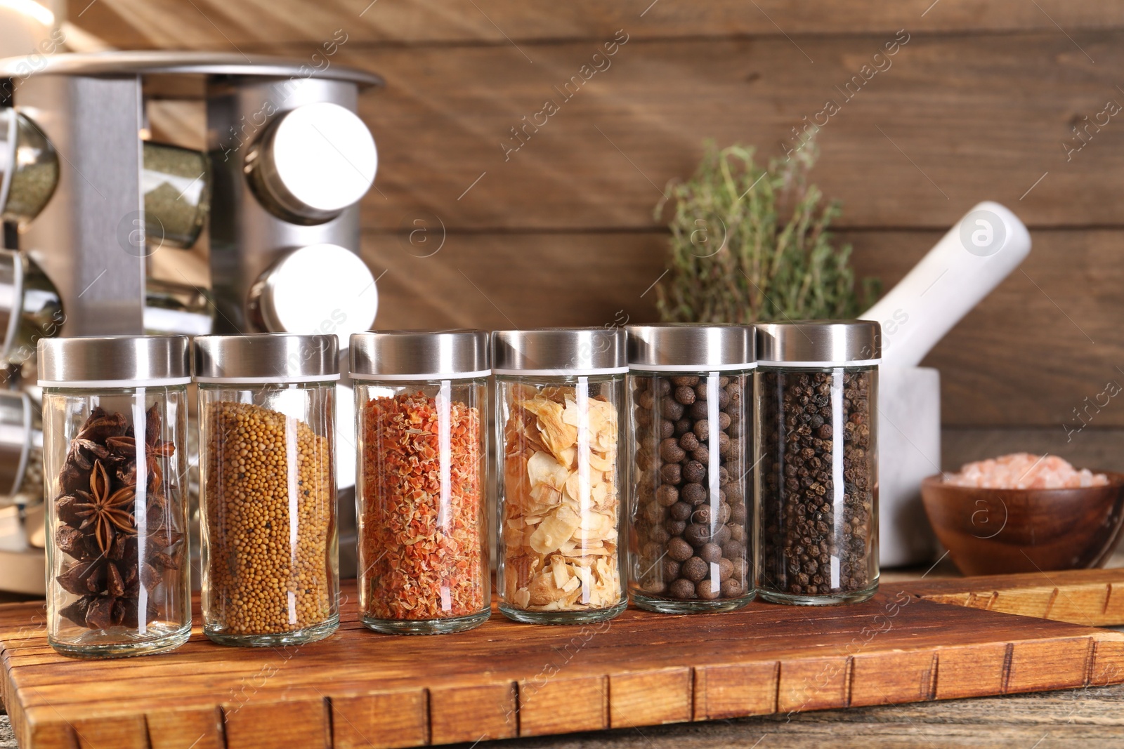 Photo of Different spices in glass jars and on wooden table, closeup