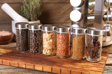 Photo of Different spices in glass jars and on wooden table, closeup