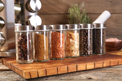 Photo of Different spices in glass jars and on wooden table, closeup