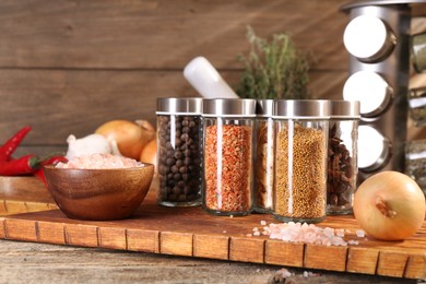 Photo of Different spices in glass jars and on wooden table, closeup