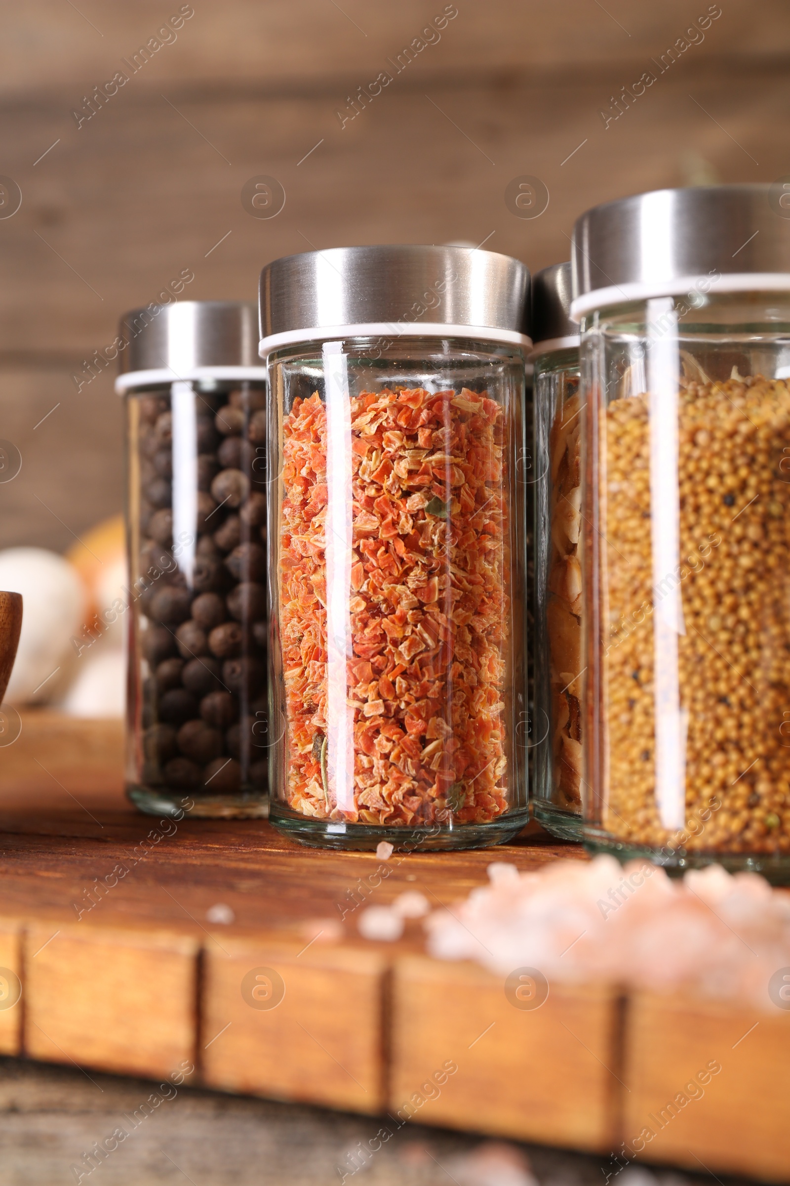 Photo of Different spices in glass jars and on wooden table, closeup